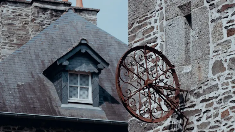 Toit d'ardoise avec lucarne et façade en pierre d'une maison ancienne de Bretagne