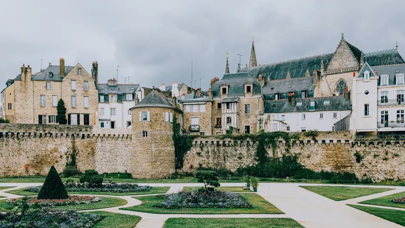 Remparts de Vannes avec une tour ronde, la vieille ville et la cathédrale derrière des jardins à la française