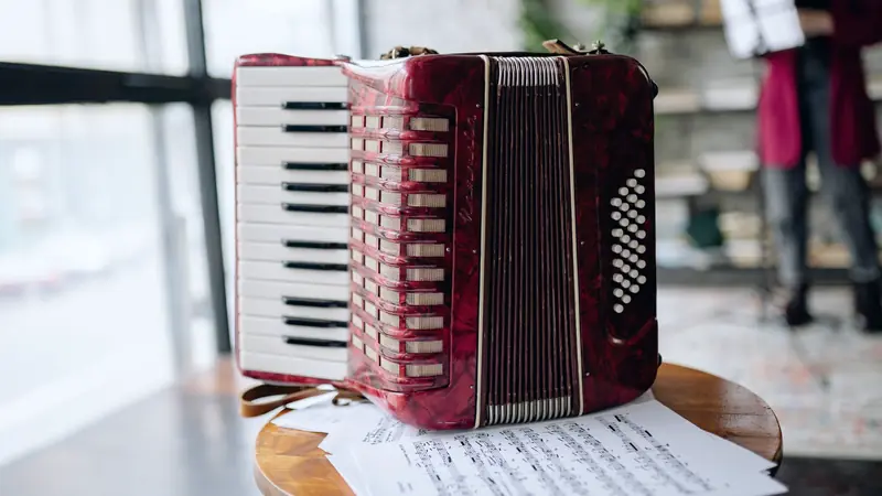Accordéon rouge posé sur un tabouret de bois au-dessus de partitions