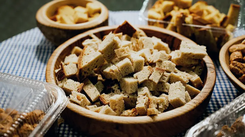 Dés de pain sec dans des bols en bois sur une nappe à carreaux bleus
