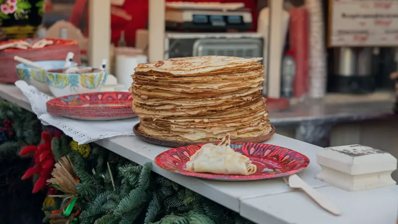 Haute pile de crêpes fines sur un plat, sur l'étal d'un stand de crêpes