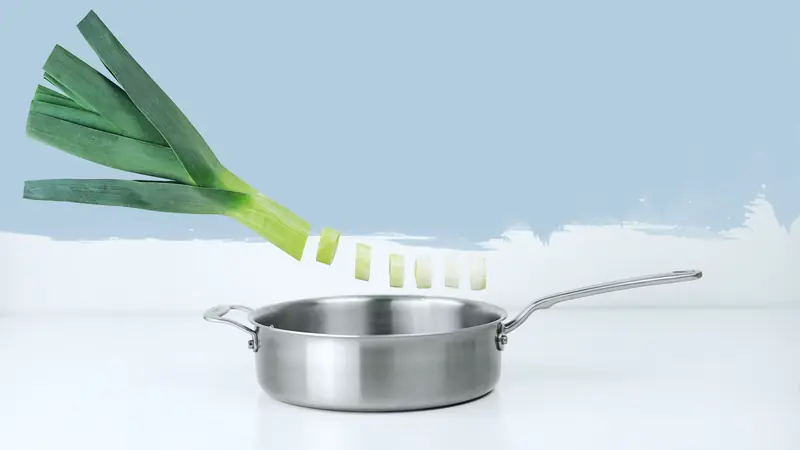 Rondelles de poireau tombant dans une sauteuse en inox
