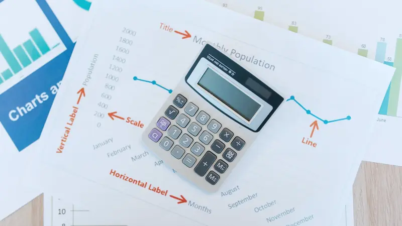 Calculatrice posée sur des feuilles de graphiques et de tableaux chiffrés