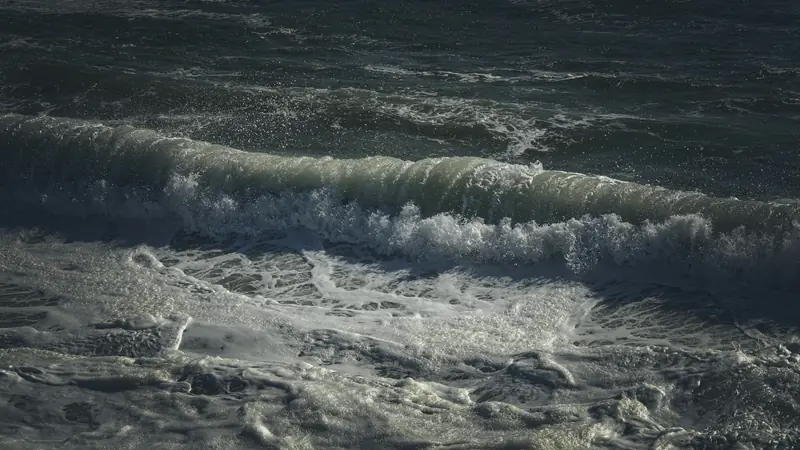 Vague qui déferle sur une mer sombre et couverte d'écume