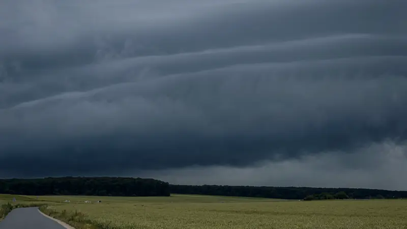 Ciel d'orage très sombre au-dessus d'un champ et d'une route de campagne